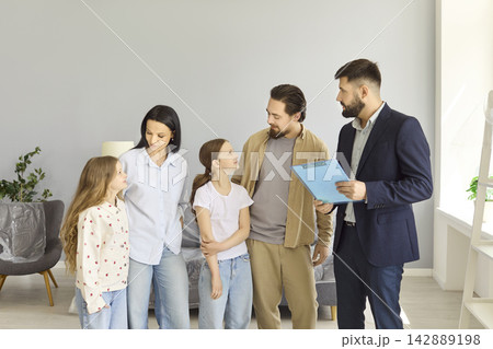 Smiling family consulting with real estate agent about new home purchase indoors Smiling family consulting with real estate agent about new home purchase indoors 142889198