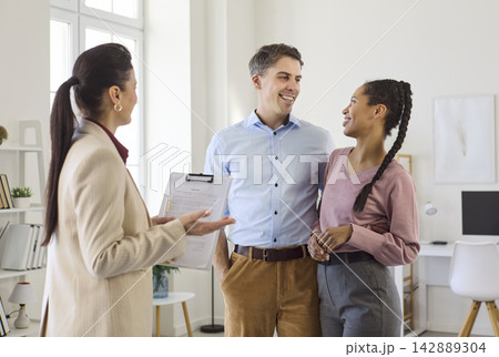 Happy couple with realtor in apartment discussing contract for rental or purchase 142889304