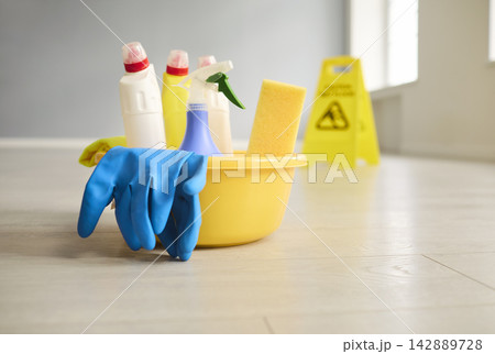 Yellow bucket of cleaning supplies with gloves and sponge, floor caution sign Yellow bucket of cleaning supplies with gloves and sponge, floor caution sign 142889728