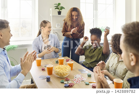 Friends cheering poker win at home table during joyful social game night Friends cheering poker win at home table during joyful social game night 142889782