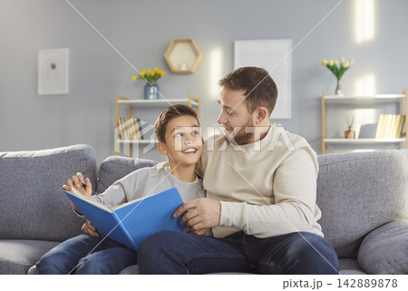 Father and son, happy loving family reading book at home, young parent with cute little child Father and son, happy loving family reading book at home, young parent with cute little child 142889878