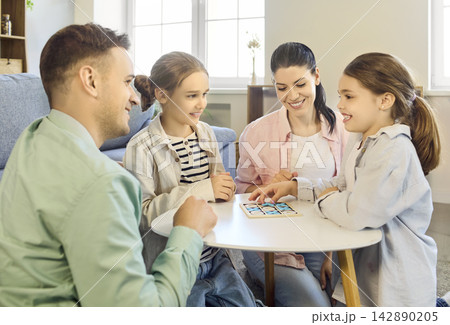 Smiling family playing board game at home, parents and kids enjoying quality time Smiling family playing board game at home, parents and kids enjoying quality time 142890205
