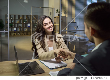 Smiling client shaking hands with advisor after contract signing in office Smiling client shaking hands with advisor after contract signing in office 142890245