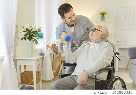 Man physiotherapist helps mature handicapped male patient to do physical exercises Man physiotherapist helps mature handicapped male patient to do physical exercises 142890336