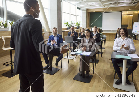 Business team applauds speaker after corporate workshop in modern office classroom Business team applauds speaker after corporate workshop in modern office classroom 142890348