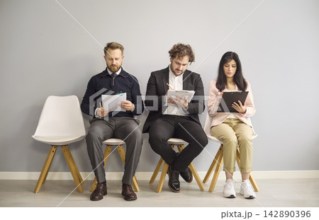 Applicants seated for recruitment interview filling forms while awaiting hiring Applicants seated for recruitment interview filling forms while awaiting hiring 142890396