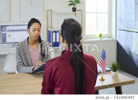 Immigration consultant meeting with client for visa application review in office Immigration consultant meeting with client for visa application review in office 142890493