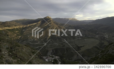 Golden Glow Highlights Winding Mountain Road. Remote Valley Houses Amid Rugged Terrain And Scenic Vistas. Creative 142890700