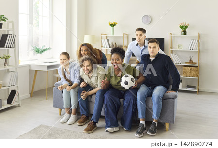 Friends intensely watching sports at home, focused on tense championship match Friends intensely watching sports at home, focused on tense championship match 142890774
