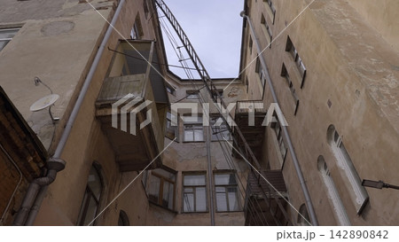 Closeup Of Building Fire Escape Fixtures. Rusty Metal Ladder And Satellite Dish On City Building. Creative 142890842