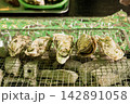炭火の網の上で香ばしく焼かれる殻付き牡蠣のクローズアップ（海鮮バーベキュー） 142891058