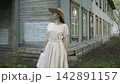 Woman in Light Dress Standing by Old Wooden House 142891157