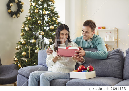 Husband Giving A Gift To Wife During New Year Or Christmas Celebration At Home Husband Giving A Gift To Wife During New Year Or Christmas Celebration At Home 142891158