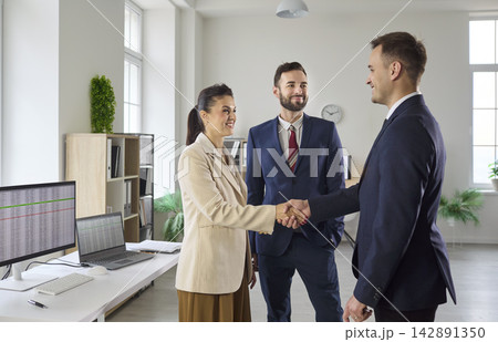 Business partners handshake in bright office after meeting with team and manager Business partners handshake in bright office after meeting with team and manager 142891350