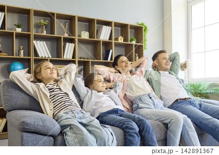 Happy family with parents and children relaxing together on sofa at home Happy family with parents and children relaxing together on sofa at home 142891367