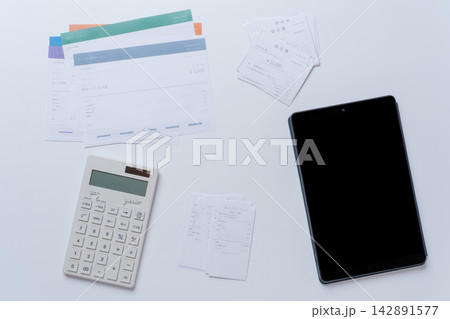 タブレットと電卓、領収書や請求書を並べた確定申告・経理のイメージ 142891577