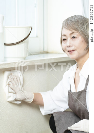 リビングで拭き掃除をするシニア女性 リビングで拭き掃除をするシニア女性 142891715