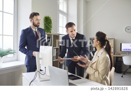 Business team discussing strategy at computer in modern office, planning analysis 142891828
