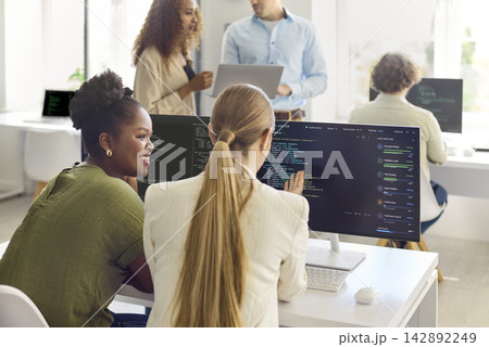 Diverse developers collaborating on code in modern office teamwork and technology 142892249