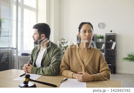 Distant couple at divorce consultation in lawyer office, gavel and papers on desk 142892592