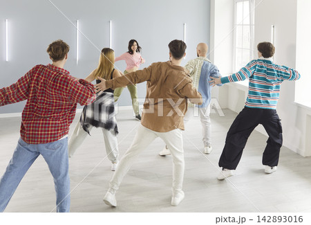 Dancing group of people actively dancing indoors, moving together with trainer in class Dancing group of people actively dancing indoors, moving together with trainer in class 142893016