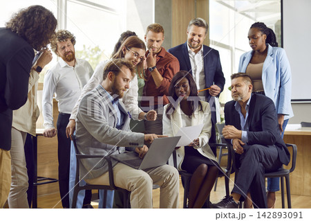 Team of diverse business men and women using laptop during work meeting in office Team of diverse business men and women using laptop during work meeting in office 142893091