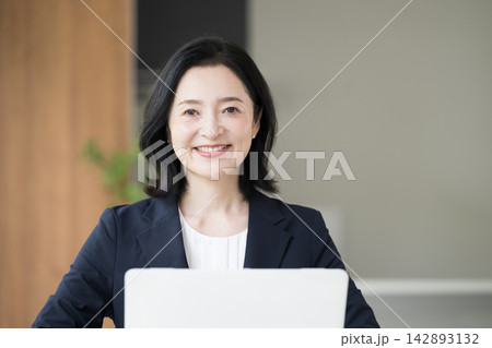 ノートパソコンで仕事をする女性会社員、オフィスで笑顔で働くビジネスウーマンのデスクワーク 142893132
