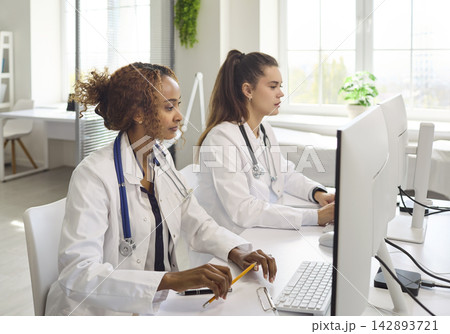 Doctors at computers updating electronic medical records in modern clinic office 142893721