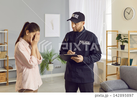 Police Officer Investigating Crime And Interviewing Crying Woman Victim At Home 142893897