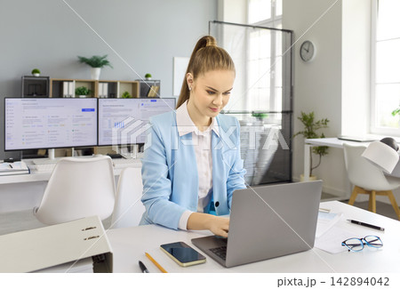 Young financial analyst businesswoman typing on laptop at modern office desk Young financial analyst businesswoman typing on laptop at modern office desk 142894042