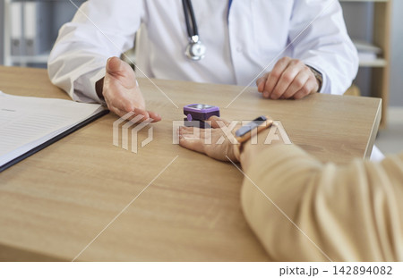 Doctor using electronic oximeter to measure peripheral blood oxygen saturation of patient Doctor using electronic oximeter to measure peripheral blood oxygen saturation of patient 142894082