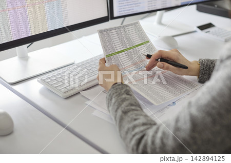 Accountant auditing financial spreadsheet data at dual monitors in office Accountant auditing financial spreadsheet data at dual monitors in office 142894125