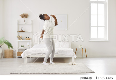 Happy African American Woman Dancing In Bedroom Celebrating A New Day Happy African American Woman Dancing In Bedroom Celebrating A New Day 142894385