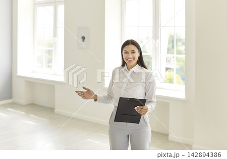 Happy smiling woman realtor agent standing in new apartments and looking at camera. 142894386