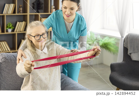 Home physiotherapy with nurse aiding senior woman using resistance band exercise Home physiotherapy with nurse aiding senior woman using resistance band exercise 142894452