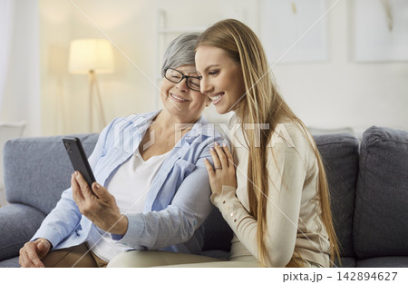 Young adult woman teaches her senior mother how to use modern technology Young adult woman teaches her senior mother how to use modern technology 142894627