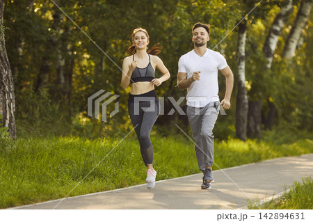Happy young jogging in sunny green park and enjoying morning run and healthy lifestyle 142894631