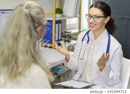 Female doctor advising senior patient in clinic during consultation and diagnosis 142894712