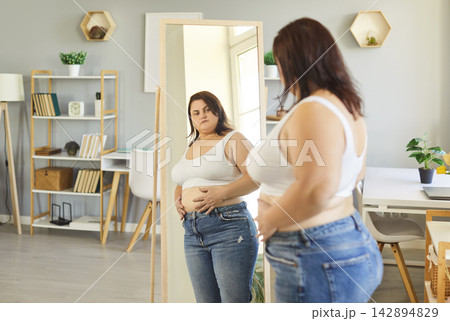 Obese woman posing in front of mirror at home wearing sporty top, chubby overweight plus size lady Obese woman posing in front of mirror at home wearing sporty top, chubby overweight plus size lady 142894829