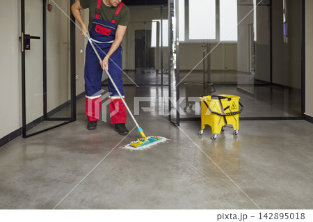 Janitor mopping office corridor floor with mop and bucket, professional cleaning Janitor mopping office corridor floor with mop and bucket, professional cleaning 142895018