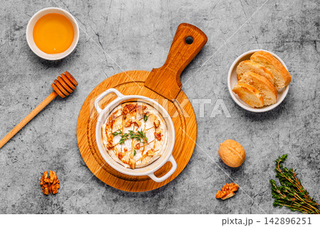 Baked cheese with honey and walnuts on a wooden board 142896251