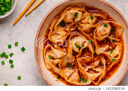 Wontons are placed in a bowl with spicy sauce. Wontons are placed in a bowl with spicy sauce. 142896534
