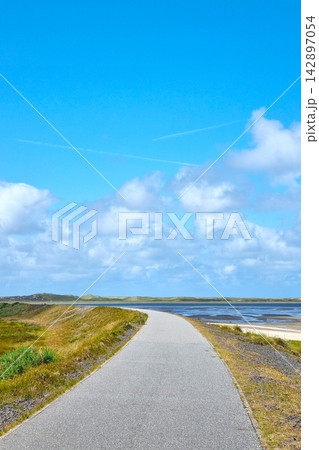 Scenic Coastal Pathway under Vibrant Blue Sky: Tranquility and Adventure 142897054