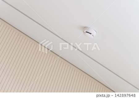 Smoke detector mounted on a white ceiling 142897648