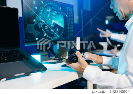 Air traffic control operators wearing headsets monitor live flight radar and navigate airspace data on screens Air traffic control operators wearing headsets monitor live flight radar and navigate airspace data on screens 142898004
