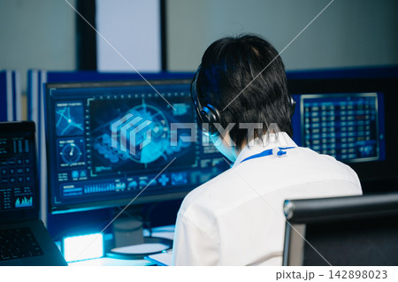 Asian people working with computers and headsets in a modern control room, monitoring digital screens, recording information, and coordinating operations. Asian people working with computers and headsets in a modern control room, monitoring digital screens, recording information, and coordinating operations. 142898023
