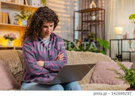 Young woman on home sofa reacting to bad laptop news with stress after job interview failure indoors 142898297