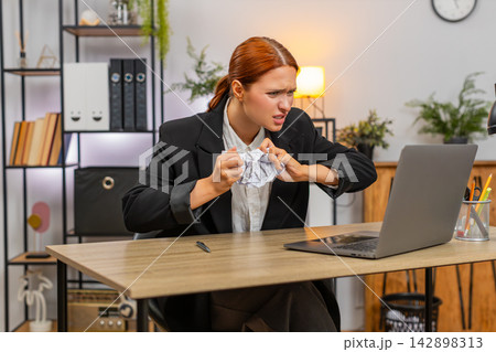 Young businesswoman reacts to report mismatch on laptop crushes paper angrily and fears audit ahead Young businesswoman reacts to report mismatch on laptop crushes paper angrily and fears audit ahead 142898313