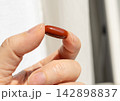 Brown gel pills, dark red capsules close up 142898837