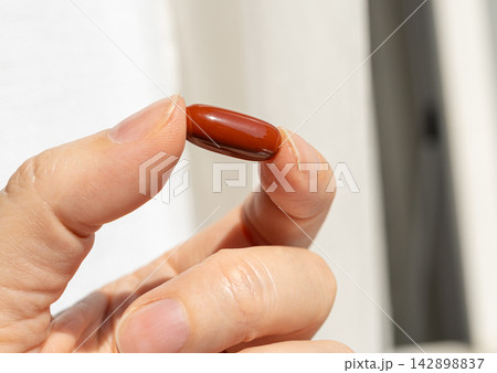 Brown gel pills, dark red capsules close up Brown gel pills, dark red capsules close up 142898837